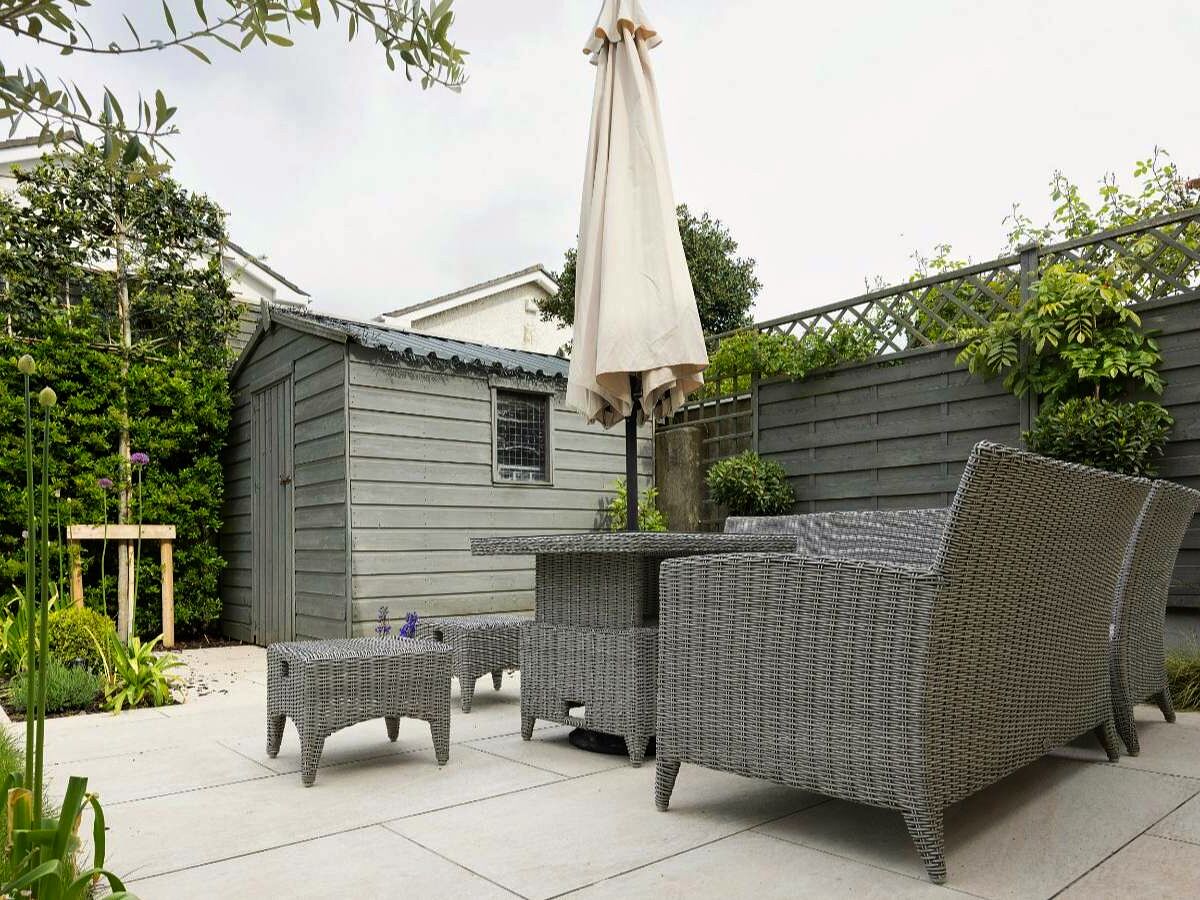 Backyard concrete patio with outdoor furniture and an umbrella