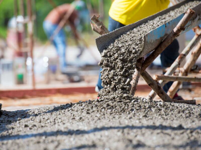 Wet concrete running down a mixer truck chute onto a prepared slab