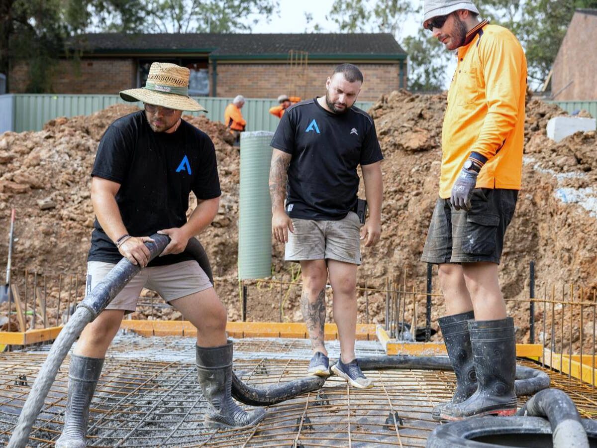Crew pumping concrete onto a rebar mat for a slab