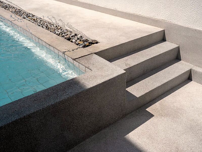 Exposed aggregate concrete steps and the edge of a pool deck