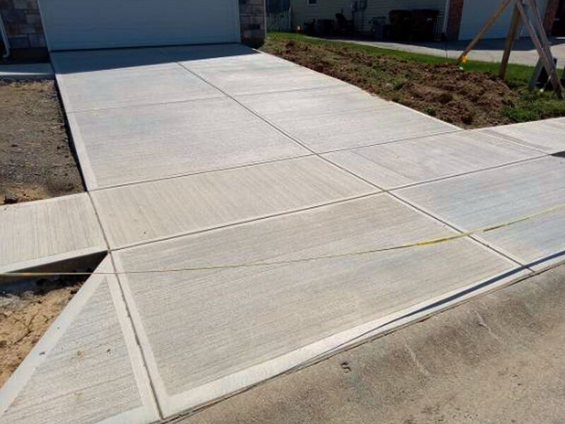 New concrete driveway with fresh saw-cut joints at the garage apron