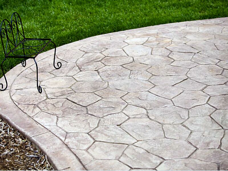 Stamped concrete patio in a random flagstone pattern with a metal chair on it